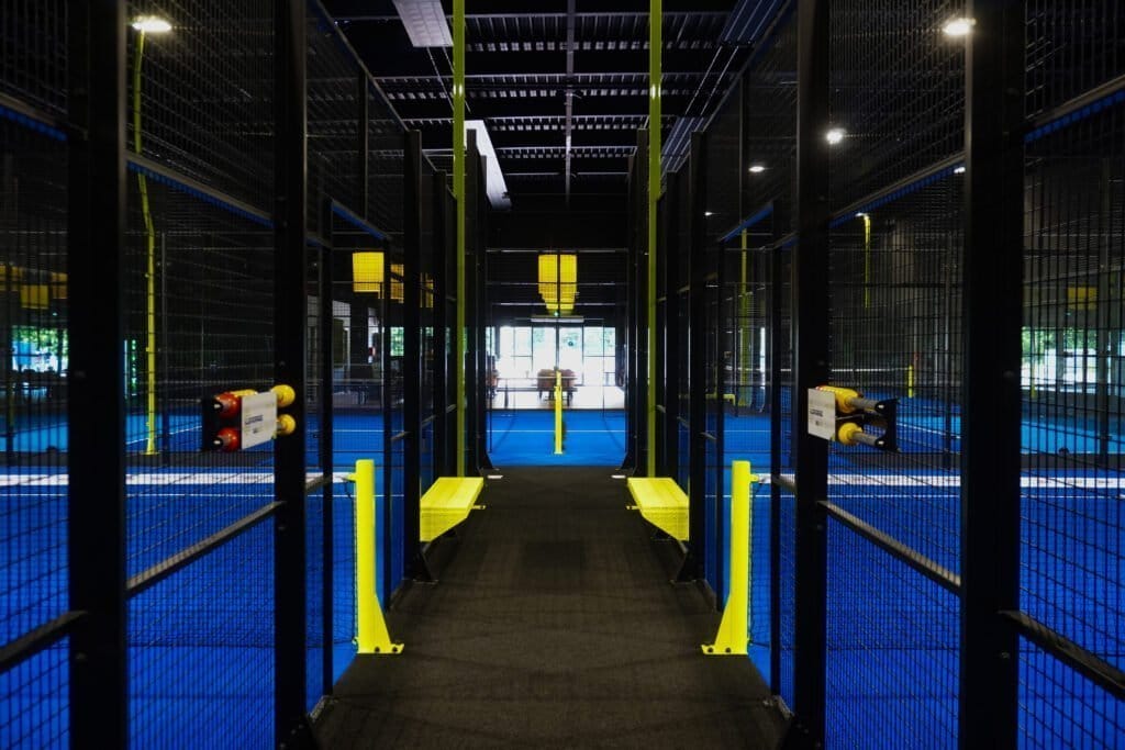 Indoor padelbanen met gele bankjes bij PADEL2GO
